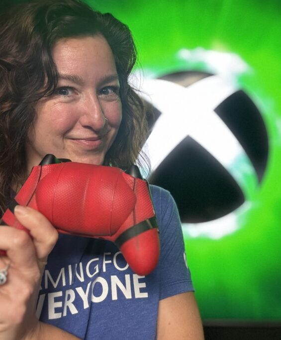 ワンダー ストームブレーカー氏の顔写真 赤いウルヴァリン仕様のXboxコントローラーを持ち、Gaming for Everyone Tシャツを着て笑顔でXboxロゴの前にいる